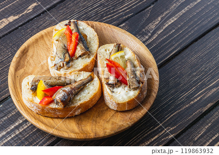 fish sandwich with butter and sprats lemon and red pepper on a dark table 119863932