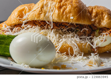 Croissant sandwich with tuna, egg, cucumber on a white plate, close up view 119863945