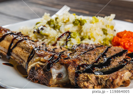 entrecote on the bone with rice and vegetables on a white plate, close-up view entrecote on the bone with rice and vegetables on a white plate, close-up view 119864005