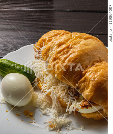 Croissant sandwich with tuna, egg, cucumber and cheese on a white plate Croissant sandwich with tuna, egg, cucumber and cheese on a white plate 119864007