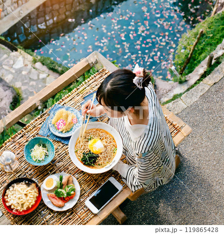 桜散る公園で食事をする女の子 119865428