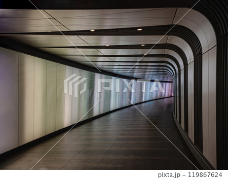 Underground pedestrian foot tunnel featuring with LED integrated lightwall with ceramic tiles spread across the floor in a large triangular pattern, in two shades to create a subtle texture 119867624