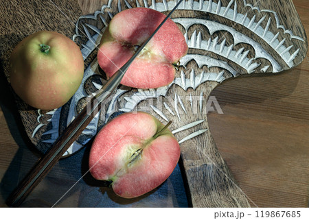 Fresh kissabel apple fruit and Cut the apple in each half with knife on wooden cutting board. Fresh kissabel apple fruit and Cut the apple in each half with knife on wooden cutting board. 119867685