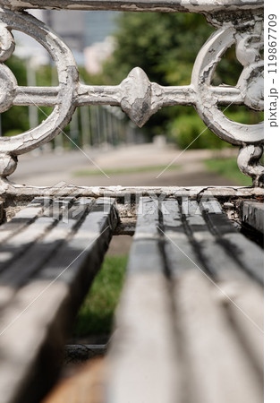 Close-up of White painted cast iron victorian style garden bench in city park. 119867709