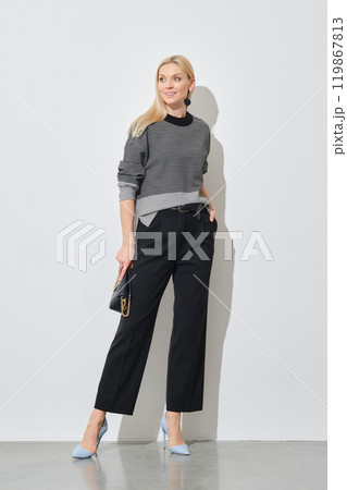 A fashionable woman poses in a striped top and black trousers 119867813