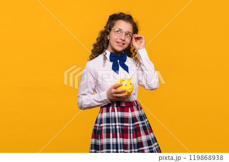 Girl adjusting glasses while holding yellow piggy bank. Girl adjusting glasses while holding yellow piggy bank. 119868938