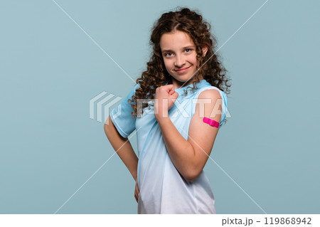Girl flexing arm with pink bandage after receiving vaccine shot. Girl flexing arm with pink bandage after receiving vaccine shot. 119868942
