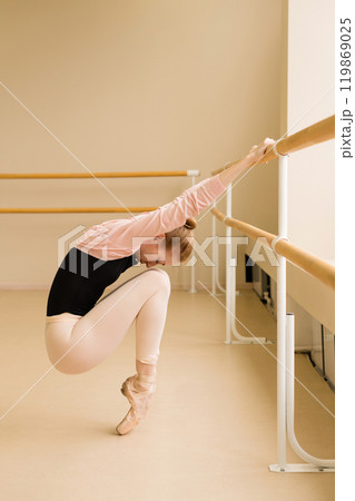 Ballet dancer balancing on pointe at barre Ballet dancer balancing on pointe at barre 119869025