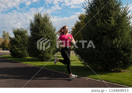 Female runner in park, jogging with headphones Female runner in park, jogging with headphones 119869053