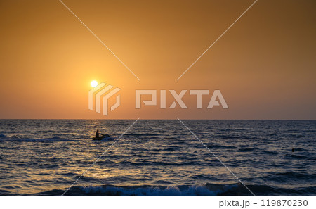 Calm sea with sunset sky and sun through the clouds over 119870230