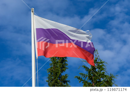 The Russian flag waves proudly against a backdrop of blue sky and green trees on a sunny day in a serene outdoor setting The Russian flag waves proudly against a backdrop of blue sky and green trees on a sunny day in a serene outdoor setting 119871174