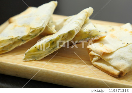 Lavash with baked cheese. Lavash with baked cheese on a wooden board. Lavash with cheese. 119871318