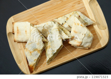 Lavash with baked cheese. Lavash with baked cheese on a wooden board. Lavash with cheese. 119871323