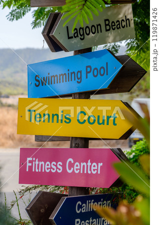 Colorful signpost guiding visitors to Lagoon Beach, swimming pool, tennis court, fitness center, and Californian restaurant in sunny surroundings 119871426