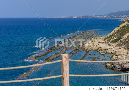 Majestic coastal view featuring rocky formations and calm blue waters along a sunlit shore in the afternoon 119871562