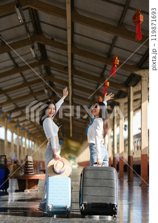 Two women are standing in a train station with their luggage Two women are standing in a train station with their luggage 119871693