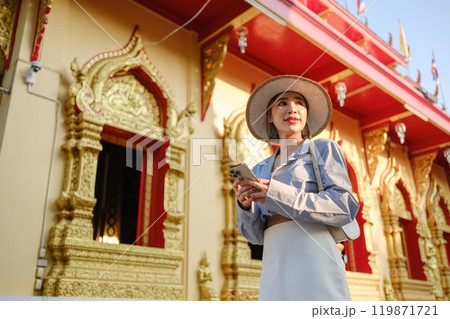 A woman wearing a straw hat is standing in front of a building with gold trim 119871721