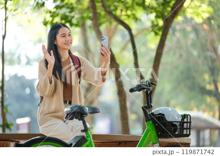 A woman is sitting on a bench with a green bike next to her A woman is sitting on a bench with a green bike next to her 119871742