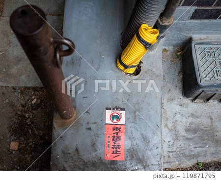 地面に煙草ポイ捨て禁止警告が設置されている風景 119871795