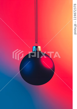 A black christmas ornament hanging from a string on a red and blue background 119872378