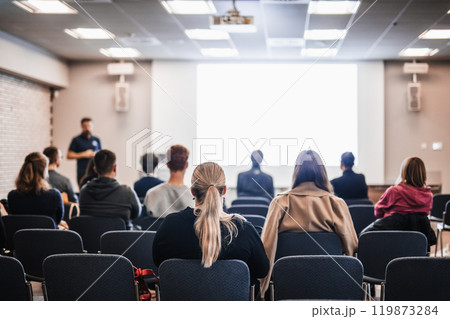Speaker giving a talk in conference hall at business event. Rear view of unrecognizable people in audience at the conference hall. Business and entrepreneurship concept 119873284
