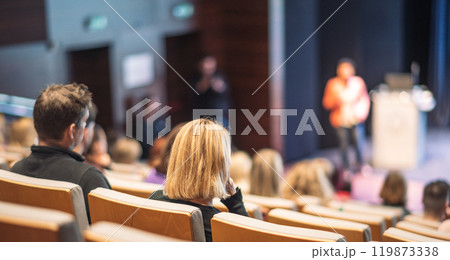 Business and entrepreneurship symposium. Female speaker giving a talk at business meeting. Audience in conference hall. Rear view of unrecognized participant in audience. Business and entrepreneurship symposium. Female speaker giving a talk at business meeting. Audience in conference hall. Rear view of unrecognized participant in audience. 119873338
