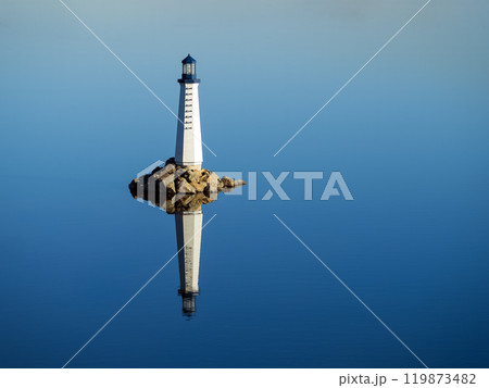 Automatic sea lighthouse reflecting in clear blue water 119873482