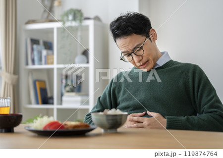 食卓でお腹に手をあてるアラフォーの男性 119874764