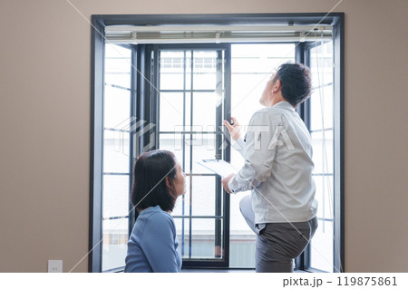 窓のサッシの点検をする修理業者と客 119875861
