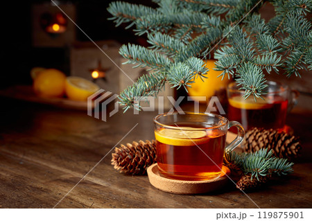 Tea with lemon and small Christmas lanterns on a wooden table. 119875901