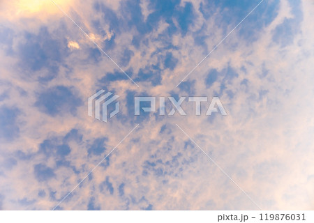 Altocumulus clouds on blue sky and sun at sunset. 119876031