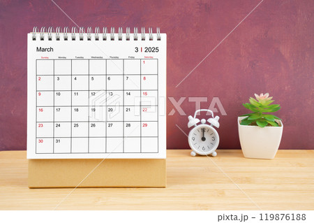 March Monthly desk calendar for 2025 year and alarm clock on wooden table. March Monthly desk calendar for 2025 year and alarm clock on wooden table. 119876188