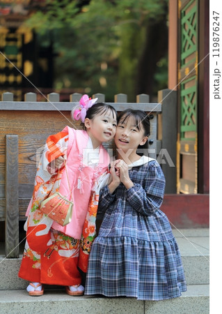 神社に七五三の参拝をする3歳の女の子と姉 119876247