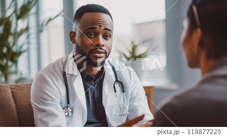 A young male handsome African American doctor in a white coat is talking with a patient in a modern office of a hospital, private clinic Public Health This is AI-generated item 119877225