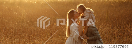 A banner family of four is walking through a field of tall grass 119877695