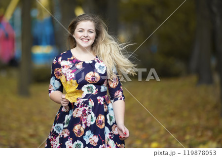 Happy blonde girl in autumn park with maple leaves. Happy blonde girl in autumn park with maple leaves. 119878053