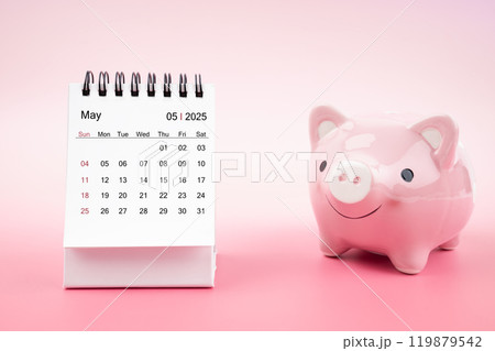 Desk calendar for May 2025 and pink piggy bank on pink background. 119879542