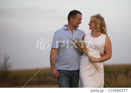 A beautiful middle-aged couple in love is walking in the field. 119880377