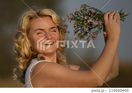 Beautiful middle-aged blonde with a bouquet of wildflowers with a smile. Beautiful middle-aged blonde with a bouquet of wildflowers with a smile. 119880400