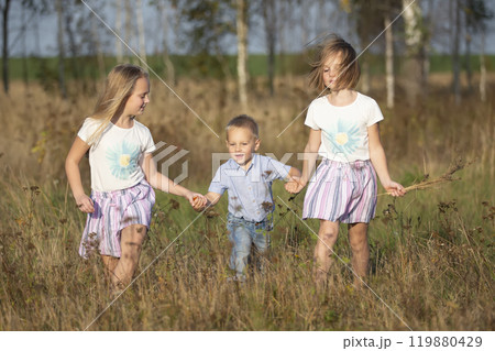 Happy family: sisters and little brother on a summer meadow. 119880429