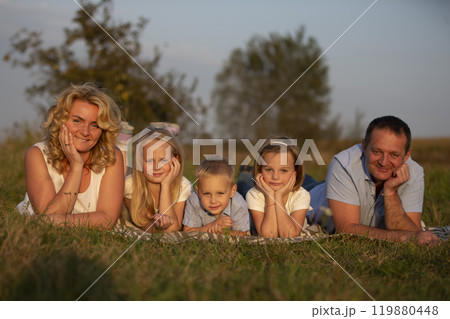 Happy family: mother, father, children, son and daughters in nature. A beautiful family lies on the grass in the park. Happy family: mother, father, children, son and daughters in nature. A beautiful family lies on the grass in the park. 119880448