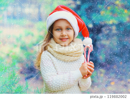 Christmas child little girl in santa red hat with sweet lollipop cane Christmas child little girl in santa red hat with sweet lollipop cane 119882002
