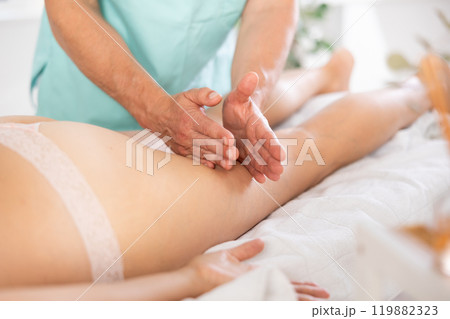 massage therapist doing a leg massage 119882323
