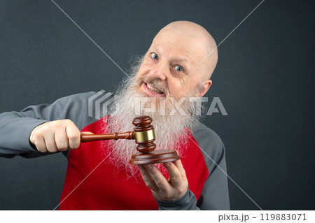bald and bearded man holds in his hands a wooden gavel for court decisions and law 119883071