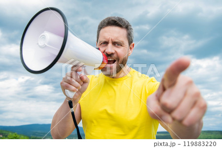 man in yellow shirt shout in loudspeaker on sky background. announcement man in yellow shirt shout in loudspeaker on sky background. announcement 119883220