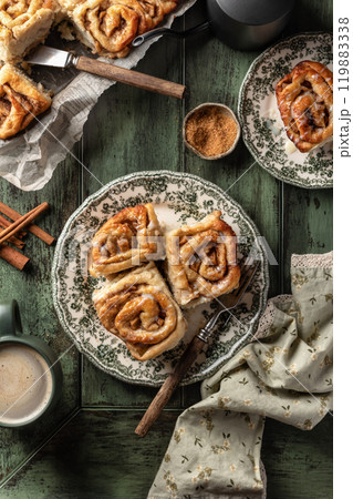 Autumn apple cinnamon rolls with frosting on green wooden background. Seasonal autumn homemade pastry cinnabons for breakfast Autumn apple cinnamon rolls with frosting on green wooden background. Seasonal autumn homemade pastry cinnabons for breakfast 119883338
