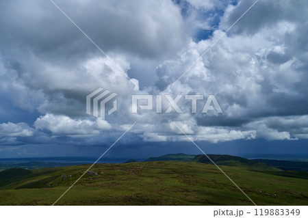 Cumulus or cluster clouds moving over a field with blue sky background in sunny weather in a wide angle shot 119883349