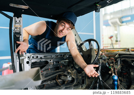 Puzzled young mechanic gesturing inside disassembled car, showcasing automotive expertise and work in progress, looking at camera with puzzled emotion. Shooting in slow motion. Puzzled young mechanic gesturing inside disassembled car, showcasing automotive expertise and work in progress, looking at camera with puzzled emotion. Shooting in slow motion. 119883685