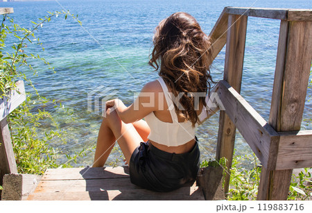 Beautiful young girl by the sea looks into the distance. 119883716
