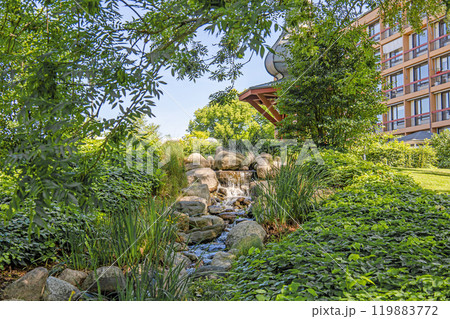 A small waterfall among large stones and green trees. 119883772